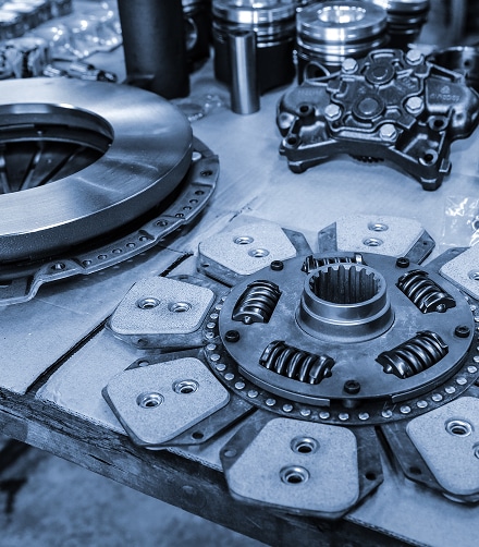 Pièces de Moteur et Embrayage pour Mécanique Automobile Disque d'embrayage et pièces de moteur de précision sur un établi dans un atelier de mécanique automobile.