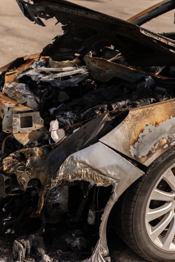 Voiture brûlée : Dégâts majeurs après un incendie moteur Voiture calcinée avec moteur fondu et carrosserie brûlée. Détails d'un véhicule après un incendie dévastateur.